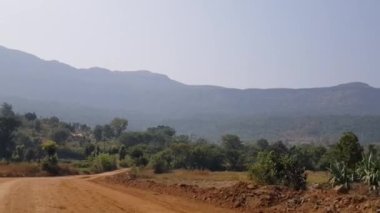 Javan Tungi yolu boyunca manzara. Yol yapım aşamasında. Hasattan sonra tarlalar boş. Bir yaz günü hareket halindeki bir araçtan çekilmiş.. 
