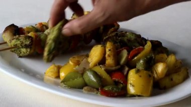 Dolmalık biberlerin yanında kızarmış tavuk parçaları ve bir tabakta ananas ve şişte ayarlanmış kemiksiz tavuk ve sebzelerle servis ediliyor. Beyaz arkaplanda çekilen. 