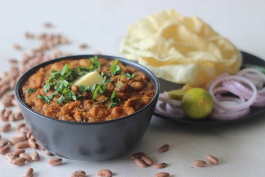 Kalın ve baharatlı soğan ve domates soslu kırmızı böbrek fasulyesi. Hindistan 'ın kuzey kesimlerinde rajma masala olarak bilinir. Beyaz arka planda papad ve soğan ile birlikte çekilmiş..