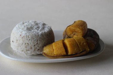 Buharda pişmiş pirinç keki ve buharda pişirilmiş muz. Kerala 'nın favori kahvaltı yemeği. Genellikle puttu ve ethakka olarak bilinir. Beyaz arkaplanda çekilen.