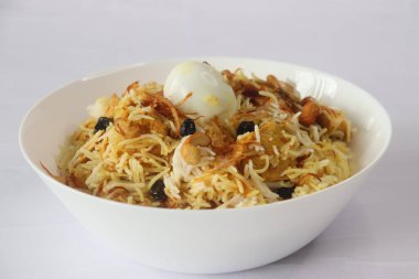 Ev yapımı tavuk biryani. Yoğurt tabanlı baharatlı tavuk soslu haşlanmış basmati, karamelli soğan, kızarmış fındık ve kuru üzümlü ghee. Beyaz arkaplanda çekilen