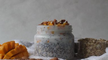 Bir gecede mango ve bademle karıştırılmış yulaf ile şişeye bal dökmek. Kahvaltı için sağlıklı ve kolay bir kombinasyon, bir önceki gece hazırlanmak için.. 