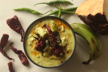 Hindistan cevizi sosunda pişirilmiş çiğ muz ve fil yer elmalı kimyon aromalı yoğurt. Halk arasında Kalan körisi olarak adlandırılan Onam yemeklerinin ana mezesi. Beyaz arkaplanda çekilen