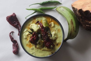 Hindistan cevizi sosunda pişirilmiş çiğ muz ve fil yer elmalı kimyon aromalı yoğurt. Halk arasında Kalan körisi olarak adlandırılan Onam yemeklerinin ana mezesi. Beyaz arkaplanda çekilen