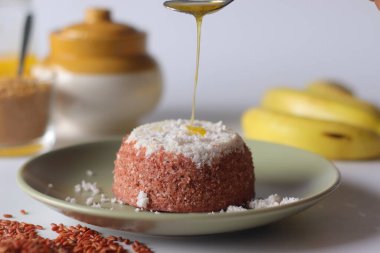 Navara pirinç puttu, geleneksel bir Güney Hindistan pilav keki, jaggery pudrası ve olgun muzlarla servis edilir. Ghee puttu 'nun üzerine dökülüyor, sıcaklığı, rahatlığı ve kültürel zenginliği çağrıştırıyor.