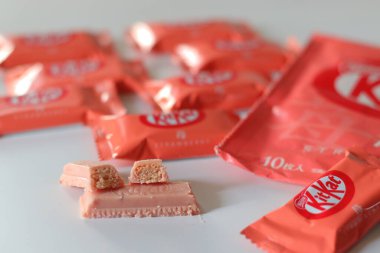 Tokyo, Japonya, 14 Aralık 2025, Çilekli KitKat çikolataları beyaz arka planda perakende ambalajla birlikte sunuluyor, Japonya 'da yaygın olarak bulunan KitKat aromalarını vurguluyor.