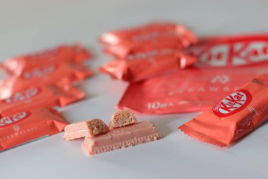 Tokyo, Japonya, 14 Aralık 2025, Çilekli KitKat çikolataları beyaz arka planda perakende ambalajla birlikte sunuluyor, Japonya 'da yaygın olarak bulunan KitKat aromalarını vurguluyor.