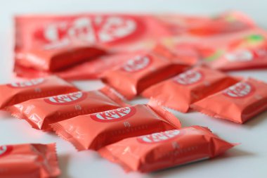 Tokyo, Japonya, 14 Aralık 2025, Çilekli KitKat çikolataları beyaz arka planda perakende ambalajla birlikte sunuluyor, Japonya 'da yaygın olarak bulunan KitKat aromalarını vurguluyor.