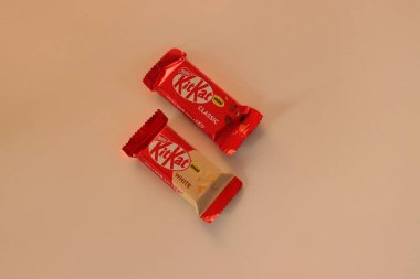 Tokyo, Japonya, 14 Aralık 2025. KitKat Mini Classic ve White çikolataları, Japon şekerleme pazarında bulunan KitKat aromalarının çeşitliliğini yansıtan sade bir yüzeyde fotoğraflanmıştır.