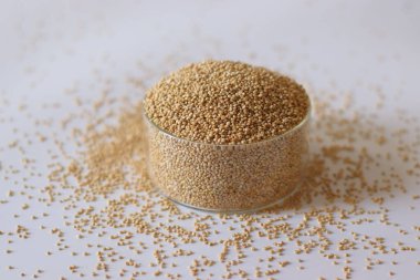 Dağınık taneciklerle dolu cam bir kasede beyaz kinoa tohumları. Protein ve lif açısından zengin tam besin. Salatalar, kaseler ve sağlıklı yemekler için glütensiz süper yiyecek.