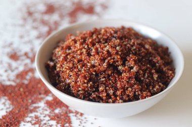 Arka planda çiğ kinoa ile servis edilen bir kasede pişirilmiş kırmızı kinoa. Bitki proteini bakımından zengin sağlıklı glütensiz süper yiyecekler, vegan ve dengeli diyet kavramı için ideal.