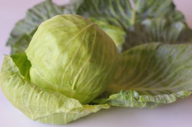 Taze yeşil lahana ve beyaz arka planda su damlacıkları yaygın olarak salatalarda, pişirmede ve vejetaryen yemeklerde kullanılan sağlıklı bir sebze.