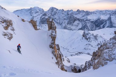 Kayakçı Joel Couloir 'a iniyor. Gün batımı ve Marmolada aralığı önde. Sass Pordoi, Dolomitas