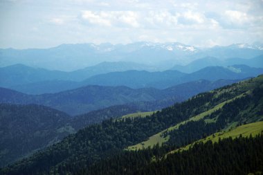 Türkiye 'de bulutlu gökyüzünün altındaki yeşil bir dağın panoramik, yüksek kaliteli görüntüsü. Bu gerçekçi ve canlı çekim doğal elementlerin mükemmel uyumunu yansıtıyor ve büyüleyici bir estetik yaratıyor..