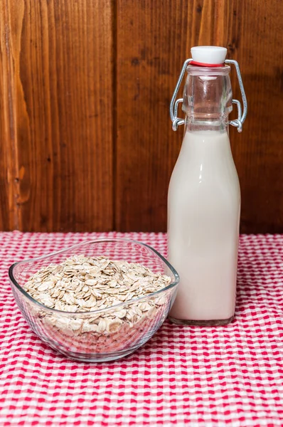 Bottiglia di latte e ciotola di farina d'avena — Foto Stock