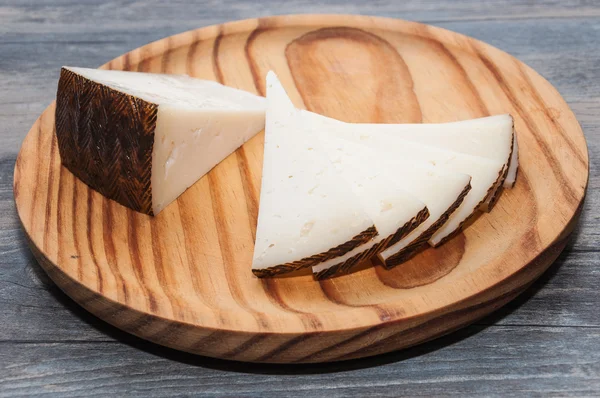 Tablero de madera con queso cortado en triángulos — Foto de Stock