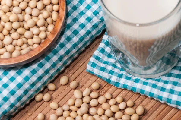 Glass of milk and bowl with soy — Stock Photo, Image