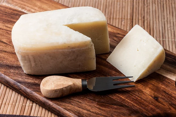 Сыр вырезан на доске и вилке — стоковое фото