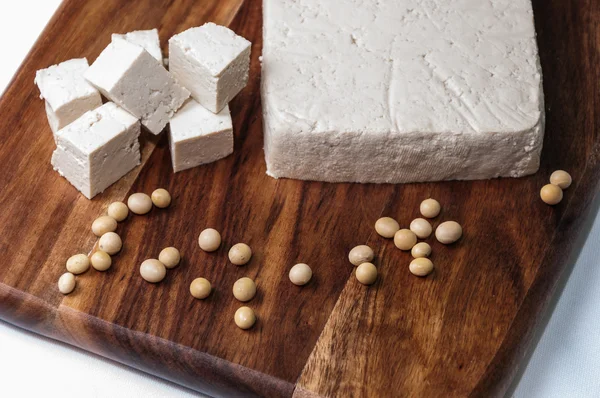 Trozo de tofu y frijoles de soya en una tabla de madera —  Fotos de Stock
