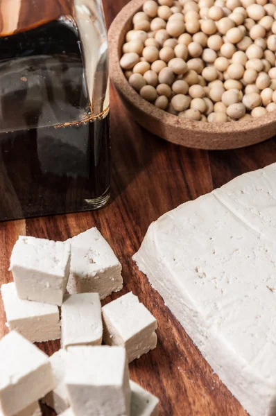 Sojová omáčka, kousek tofu a sójové boby na dřevěném prkénku — Stock fotografie