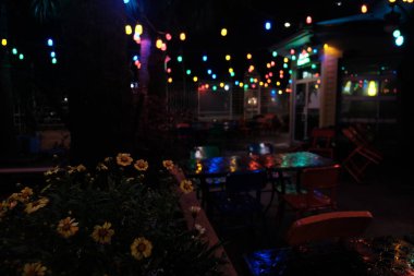 Bu Lafayette Louisiana şehir merkezindeki Agave Meksika restoranının verandasındaki fotoğraf. Geceleri serin görünüyor. Yağmurdan sonra bahçeden yansıyan renkli ışıklar ve bitkilerle..