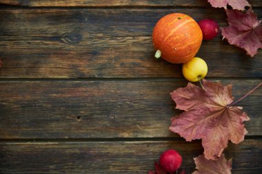 Sarı akçaağaç yaprakları, kırmızı elmalar ve balkabaklarıyla sonbahar arkaplanı. Sonbahar hasadının kopyalanmış ahşap üzerindeki çerçevesi. Mevsimlik teklifler ve tatil kartpostalları için model, üst görünüm