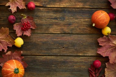 Sarı akçaağaç yaprakları, kırmızı elmalar ve balkabaklarıyla sonbahar arkaplanı. Sonbahar hasadının kopyalanmış ahşap üzerindeki çerçevesi. Mevsimlik teklifler ve tatil kartpostalları için model, üst görünüm