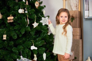 Küçük tatlı bir kız elinde Noel ağacı için bir oyuncak tutuyor..