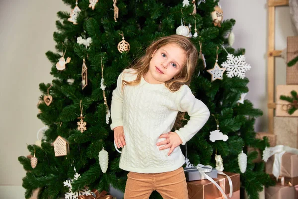 Dziewczyna w białym eko sukienka przebrana za dziewczynę Boże Narodzenie. Jest zielona choinka i prezenty z tyłu. — Zdjęcie stockowe