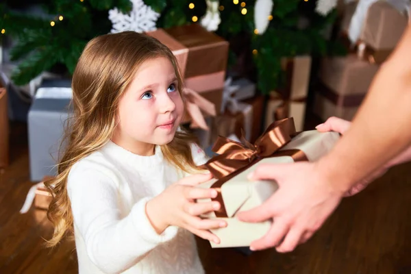 Девочка смотрит на маму, мама дарит девочке подарок на Рождество — стоковое фото