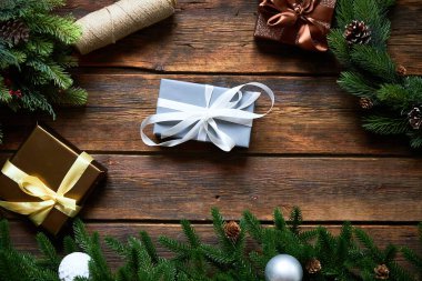 Noel ya da yeni yıl tatiline hazırlanıyorum. Düz kürk dalları, yemyeşil çelenkler, Noel hediyesi ahşap masa arkaplanı, üst manzara, kopyalama alanı.