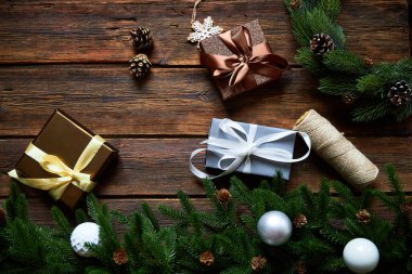 Noel ya da yeni yıl tatiline hazırlanıyorum. Düz kürk dalları, yemyeşil çelenkler, Noel hediyesi ahşap masa arkaplanı, üst manzara, kopyalama alanı.