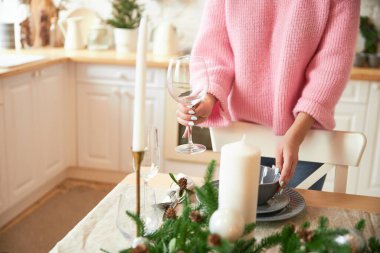 Kadın, aile tatili için beyaz mutfakta sadece elleri ve yüzü olmayan bir Noel masası servis ediyor.