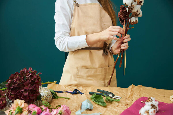 A woman florist in working clothes creates a bouquet