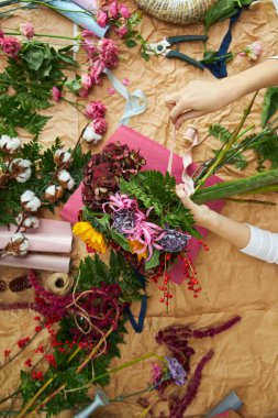 Düz kompozisyon çiçekçisi el işi kağıt ve pembe arka plan kağıdı üzerinde bir buket oluşturur.