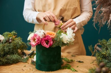 Dişi bir çiçekçi, Noel için çiçek ve ladin dallarından bir buket yapar. Bir çiçekçinin işi..