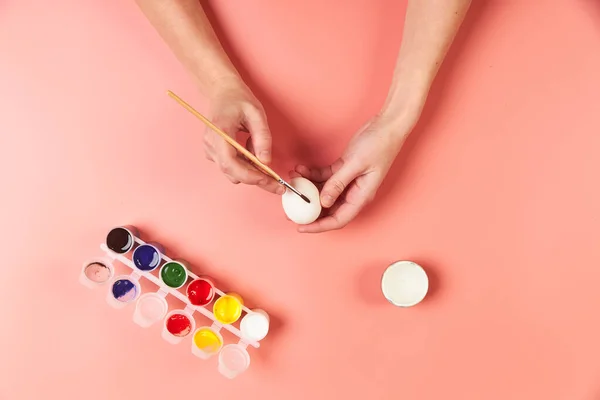 Uma menina pinta ovos para fundo rosa de Páscoa — Fotografia de Stock