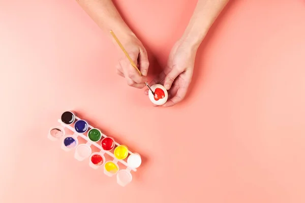 A girl paints eggs red for Easter — Stock Photo, Image