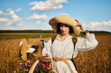 Bir kadın elinde yaz çiçekleri olan bir sepet tutuyor.