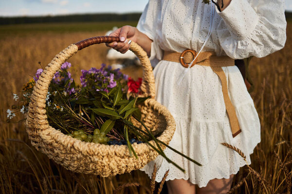 A woman holds a basket with summer wildflowers
