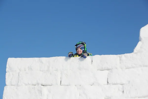 雪のブロックから壁上部のカラー ジャケットで幸せな子 — ストック写真