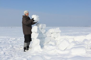 Kışın kar bloklar bir glade üzerinde bir Eskimo bina bir sakallı adam