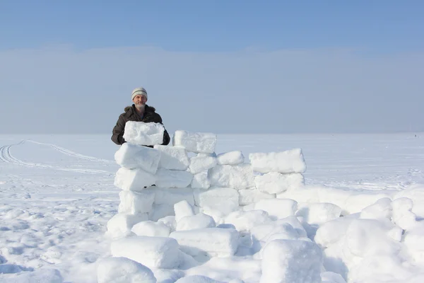 El hombre con barba que construye un iglú de bloques de nieve en un claro en invierno —  Fotos de Stock