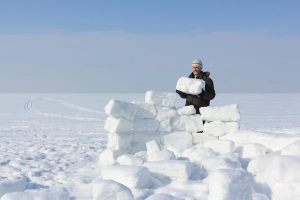 El hombre con barba que construye un iglú de bloques de nieve en un claro en invierno — Foto de Stock