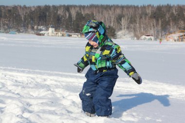 Küçük çocuk bir kukuleta ile renk ceketli kar atar