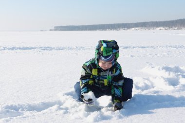 Küçük çocuk kar ile oynarken bir kukuleta ile renk ceketli