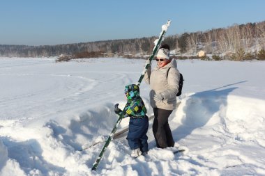 Kadın ve kar üzerinde sopa ile oynayan çocuk
