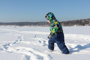 Kışın kar üzerinde çalışan bir renk ceketli çocuk