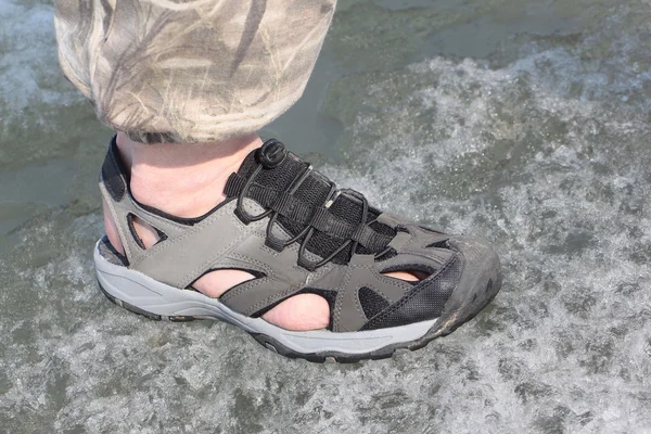 Male leg in sandals for rafting on ice of the thawing river