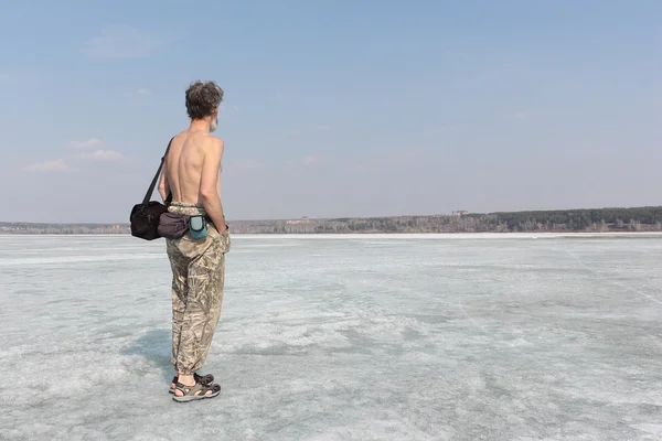 Седовласый мужчина с обнаженным туловищем идёт по льду реки — стоковое фото